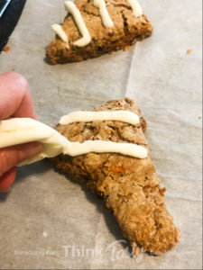 Homemade scone filled with carrots, raisins, and pecans topped with cream cheese frosting