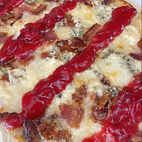 flatbread topped with bacon, blue cheese, and cranberry drizzle