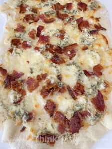 flatbread topped with bacon, blue cheese, and cranberry drizzle