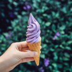 A female hand holds a lavender ice cream on the background of a lavender field